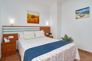 A bedroom with a bed, nightstand, and wall art. - Apartment '1D - 2 bedrooms 4-6 people' with shared pool, Wi-Fi and air conditioning (Nerja)