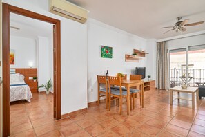 A room with a bed, a dining table with chairs, a TV, a ceiling fan, and a window with curtains. - Apartment '1D - 2 bedrooms 4-6 people' with shared pool, Wi-Fi and air conditioning (Nerja)