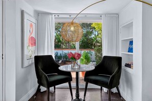 A room with a round table, two black chairs, a hanging light fixture, a framed picture, and a view through a window. - MIAMI EUROPEAN SPA LIKE HOME 10 MINUTES TO THE BEACH WALK TO GOLF COURSES (Miami Shores)