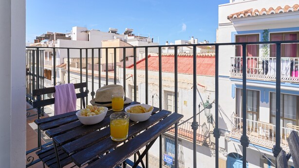 Un balcon avec une table, un bol de collations et un verre de jus d’orange.