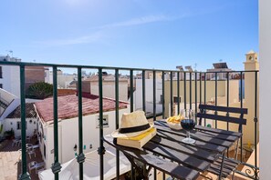 A balcony with a table, a hat, a book, a glass of red wine, and a bowl of chips. - Studio '2B Studio with Balcony for 2 Guests' with Shared Pool, Wi-Fi and Air Conditioning (Nerja)
