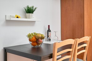 A dining table with a fruit bowl, a wine bottle, and a potted plant on a white shelf. - Studio '2B Studio with Balcony for 2 Guests' with Shared Pool, Wi-Fi and Air Conditioning (Nerja)
