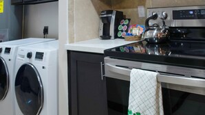 Uma cozinha com fogão, cafeteira e máquina de lavar.