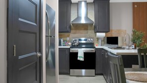 Uma cozinha moderna com armários escuros, eletrodomésticos de aço inoxidável e painel de azulejos.
