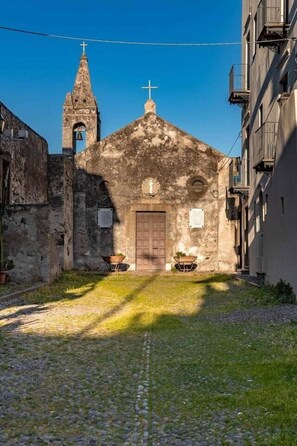 Eine Kirche mit einem Glockenturm, einer Holztür und einem kleinen Garten mit einem Schubkarren.