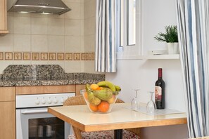 A kitchen with a granite countertop, a glass bowl of fruit, a wine bottle, and a stove. - Studio '2C with Balcony, Mountain View, Wi-Fi & Air Conditioning' (Nerja)