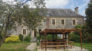 A stone building with a wooden pergola and benches in front.
