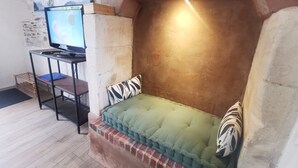 A cozy seating area with a cushioned bench, a television on a stand, and a stone wall.