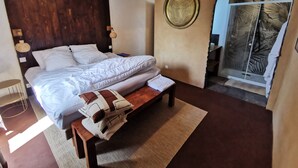 A bedroom with a bed, bedside table, bench, and a large window with a view.