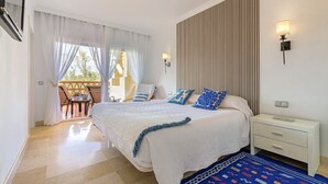 A bedroom with a bed, bedside table, and a view of the outdoors. - Luxury 2BR Resort Apt, Pools, Spa, Tennis (Estepona)