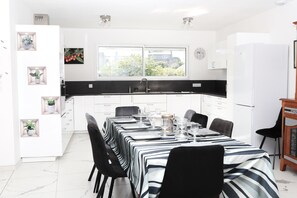 A modern kitchen with white cabinets, a black countertop, and a dining area set for six.