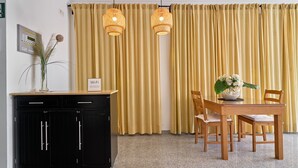 A room with a black cabinet, a wooden table with chairs, yellow curtains, and two wicker pendant lights. - Apartment '2D - 2 Bedrooms 4-6 Guests' with Shared Pool, Wi-Fi, and Air Conditioning (Nerja)