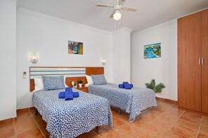A hotel room with two beds, a ceiling fan, and artwork on the walls. - Apartment '2D - 2 Bedrooms 4-6 Guests' with Shared Pool, Wi-Fi, and Air Conditioning (Nerja)