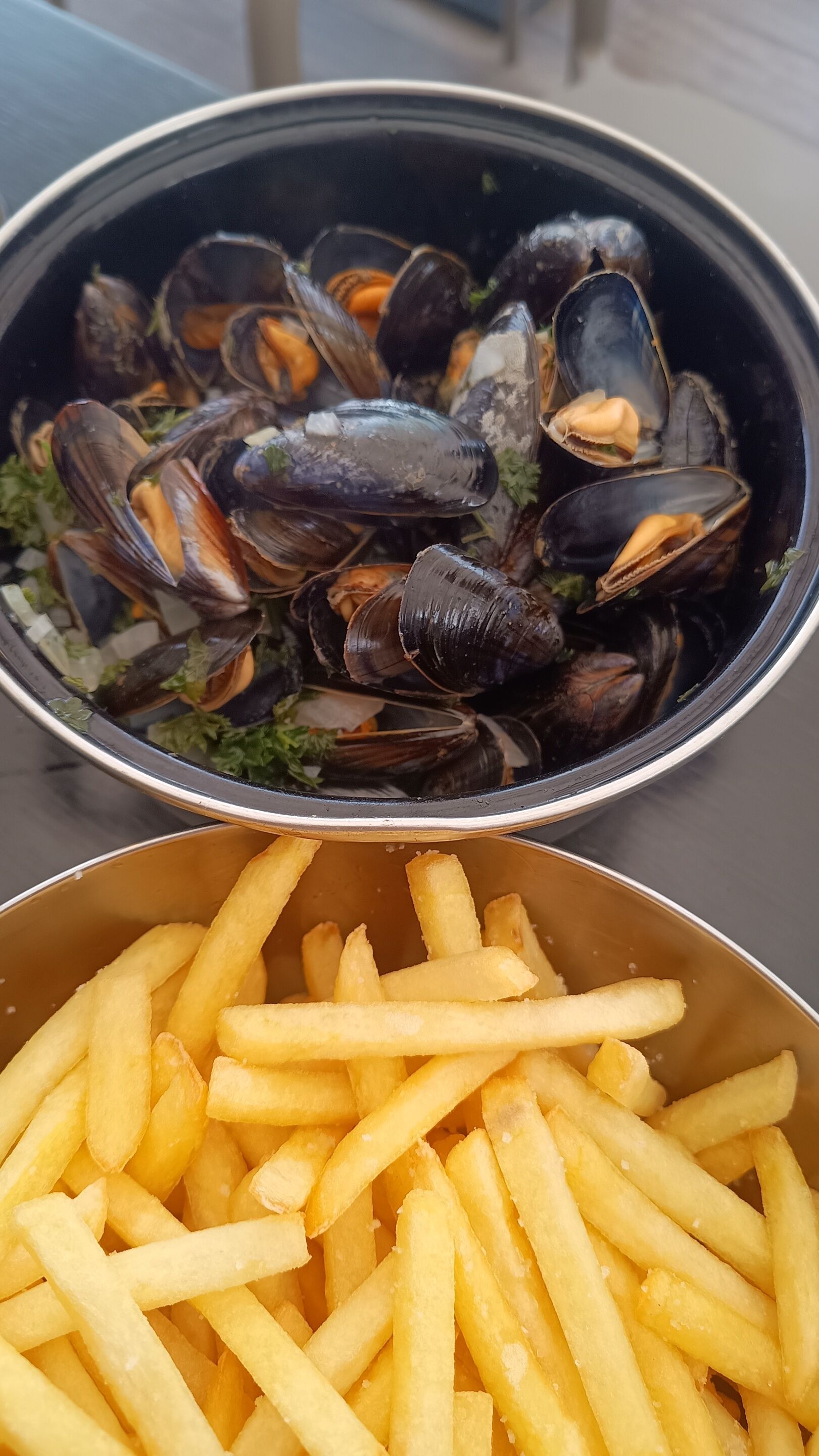 Eine Schüssel mit Muscheln und eine Portion Pommes.