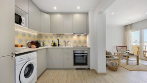 Cuina moderna amb rentadora, forn i zona de menjador amb vista.