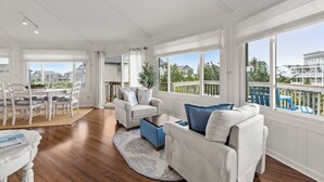 A spacious living area with a dining set, a sofa, and a view of the outside. - Short Walk to Beach | Outdoor Entertainment Area (Salvo)