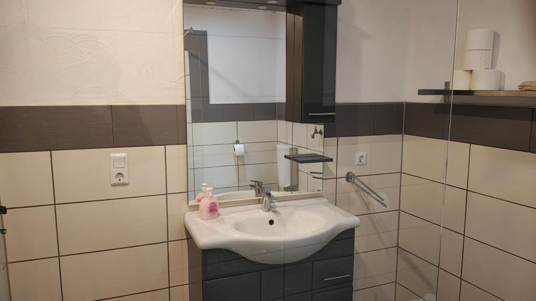 A bathroom with a sink, mirror, and towel rack.