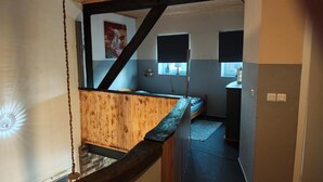 Une pièce avec un escalier en bois, un lit, une fenêtre et une petite table.