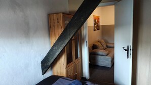 Une pièce avec un meuble en bois, un canapé et un escalier menant à une autre pièce.