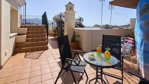 Terraço no telhado com mesa, cadeiras, um vaso de planta e uma escadaria.