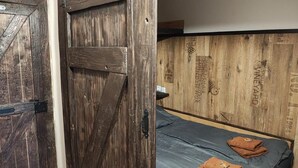 Eine rustikale Holztür, ein Bett mit blauer Matratze und eine Wand mit verschiedenen Holzwänden und Text.