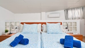 A double bed with matching blue and white patterned bedding, two bedside tables with lamps, a potted plant, and a wall-mounted air conditioner. - Apartment 'P3 Duplex 2BR for 4-6 Guests' with Pool, Wi-Fi & Air Conditioning (Nerja)