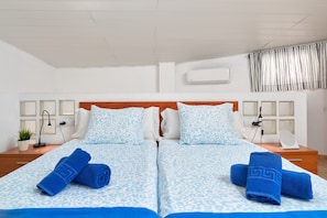 A double bed with matching blue and white patterned bedding, two bedside tables with lamps, a potted plant, and a wall-mounted air conditioner. - Apartment 'P3 Duplex 2BR for 4-6 Guests' with Pool, Wi-Fi & Air Conditioning (Nerja)