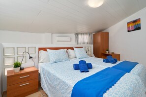 A bedroom with a bed, bedside tables, a wooden wardrobe, a wall-mounted air conditioner, and a window with curtains. - Apartment 'P3 Duplex 2BR for 4-6 Guests' with Pool, Wi-Fi & Air Conditioning (Nerja)