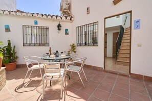 A patio with a round table and chairs, a potted plant, and a staircase leading to an upper floor. - Apartment 'P3 Duplex 2BR for 4-6 Guests' with Pool, Wi-Fi & Air Conditioning (Nerja)