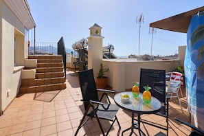 A rooftop terrace with a table, chairs, a potted plant, and a staircase. - Apartment 'P3 Duplex 2BR for 4-6 Guests' with Pool, Wi-Fi & Air Conditioning (Nerja)