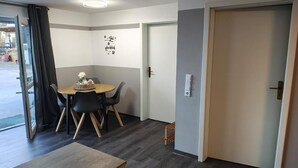 Ein Zimmer mit Esstisch, Stühlen, einer Tür und einer Wand mit dekorativem Schild.