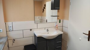 Ein Badezimmer mit einem weißen Waschbecken, schwarzen Schränken, einem Spiegel und einem Handtuchhalter.