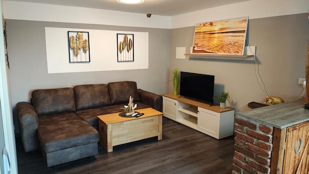 Ein Wohnzimmer mit Sofa, Couchtisch, Fernseher und Kunstwerken an der Wand.