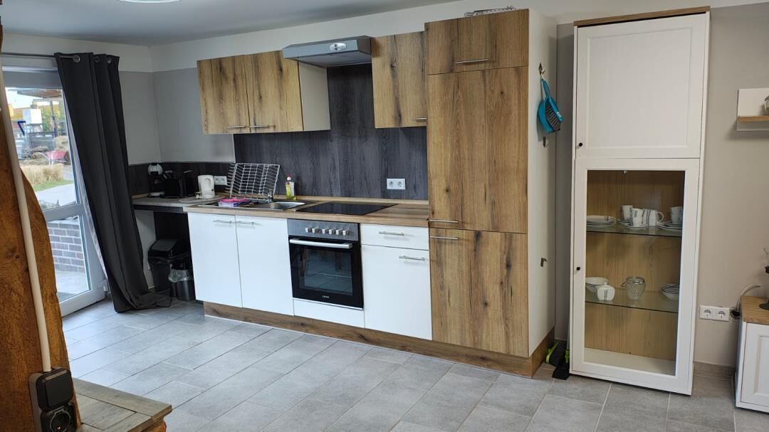 A modern kitchen with wooden cabinets, a built-in oven, and a glass-fronted cabinet.