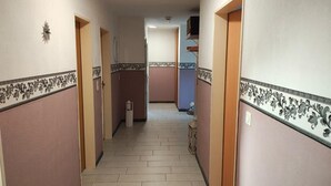En gang med tapetserede vægge, flisegulv og en dør i enden.