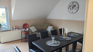 Et spiseområde med et bord dækket til fire personer, et verdenskort-ur og en radiator.