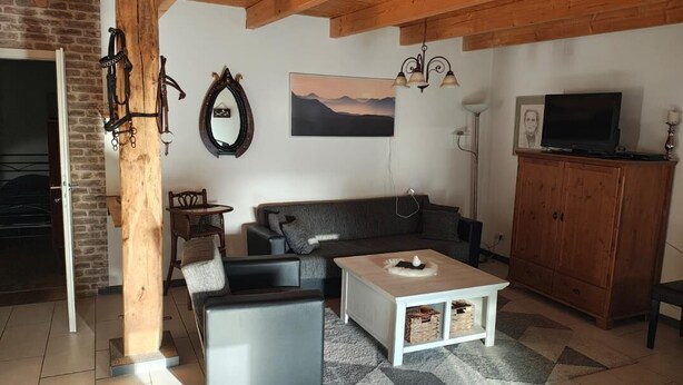 Un salon avec un canapé, une table basse et un téléviseur posé sur un meuble.