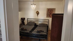 Une chambre à coucher avec un lit en métal, un lustre, une applique murale et un tableau.