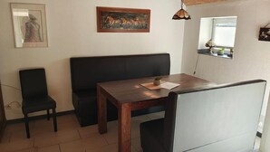 Un espace repas comprenant une table en bois, des chaises noires, un banc et des œuvres d’art accrochées aux murs.