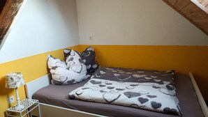 A bedroom with a bed, pillows, a nightstand, and a lamp. - Modern loft apartment No. 3 with terrace (Aurich)
