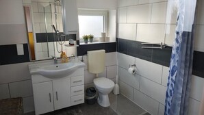 A modern bathroom with a sink, toilet, and shower. - Modern loft apartment No. 3 with terrace (Aurich)