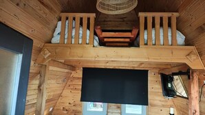 Ein Holzinnenraum mit Balkon, einem schwarzen Bildschirm und einer Holztür.