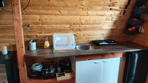 Eine kompakte Küche mit Holzwänden, einem Spülbecken, einem Geschirrspüler und einer kleinen Ablage.
