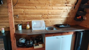 Eine kompakte Küche mit Holzwänden, einem Spülbecken, einem Geschirrspüler und einer kleinen Ablage.