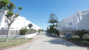 Eine Wohnstraße mit weißen Häusern, Bäumen und blauem Himmel.