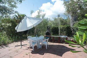 A patio with a table and chairs, a white umbrella, and a stone oven.
