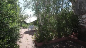 Ein Garten mit einem Pfad, einem Tisch mit Stühlen und einem Gebäude mit Strohdach.