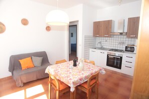A compact kitchen with white cabinets, a stove, and a microwave.