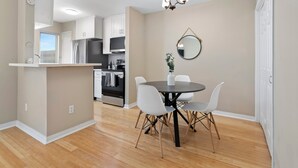 A modern kitchen with white cabinets, a black refrigerator, and a dining area with a round table and white chairs. - 2-bedroom condo in tranquil Greater Uptown, near The Galleria Mall (Houston)