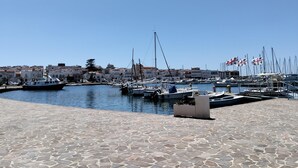 Ein Yachthafen mit vertäuten Booten, einer gepflasterten Uferpromenade und Gebäuden im Hintergrund.